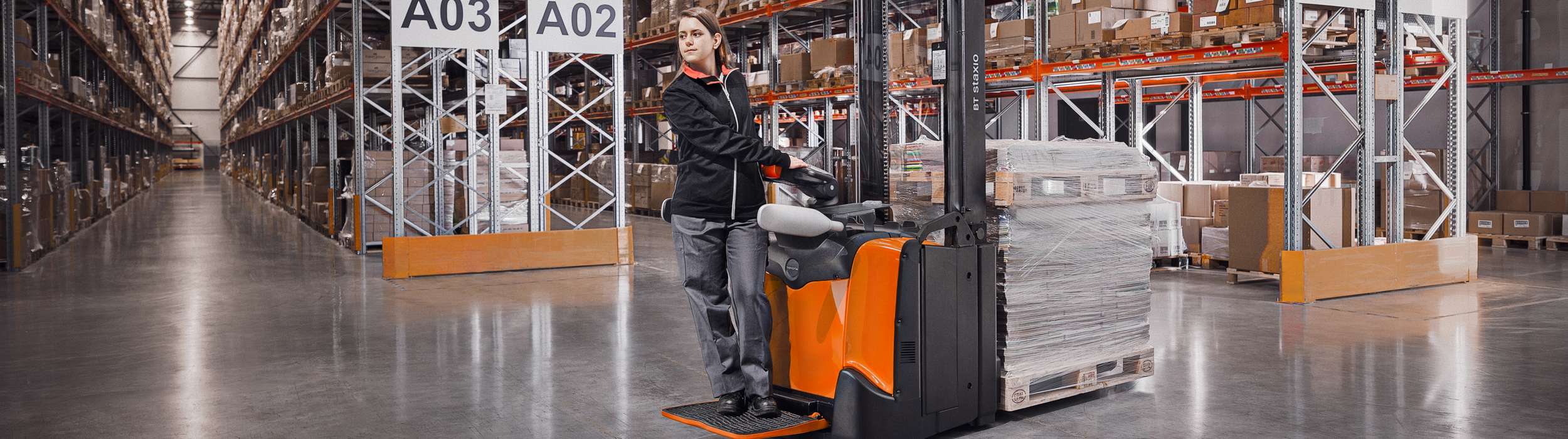 Woman driving a Staxio stacker in warehouse