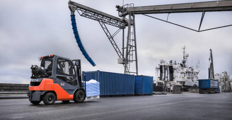 Čelní vysokozdvižný vozík přepravuje materiál v přístavu ve venkovních prostorech