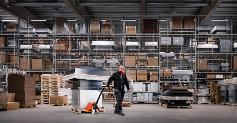 a hand pallet truck with materials loaded being dragged through a warehouse
